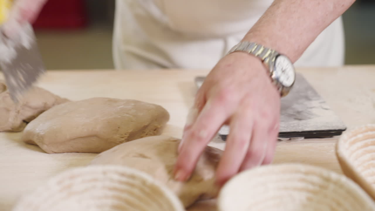Portioning dough for making bread, baker weighs dough on digital scale, man weighing dough in bakery on wooden table