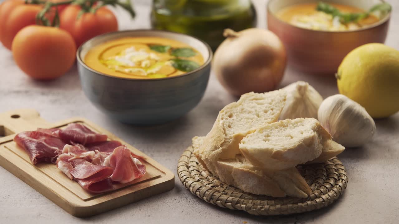 serving the bread and ham on the table, next to the salmorejo or gazpacho