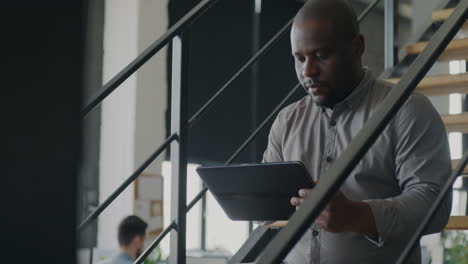 man working on a tablet on the stairs in an office
