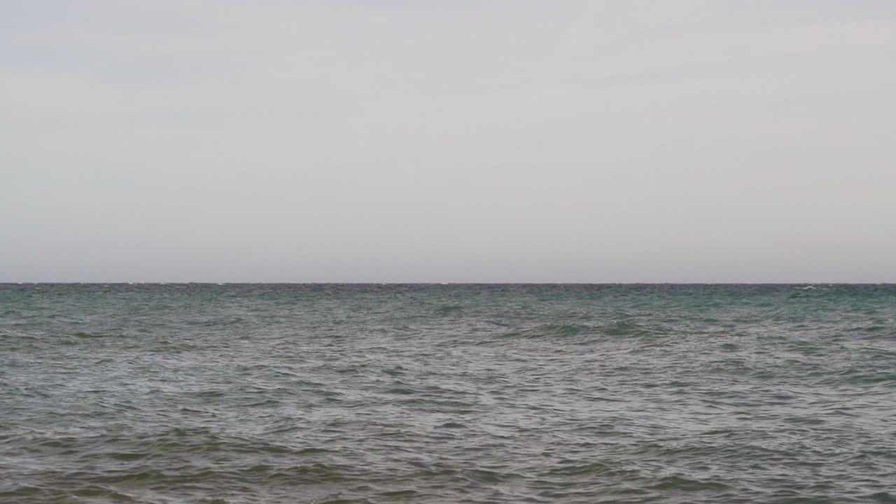 회색 하늘과 느린 동작 잔물결이 있는 미니멀한 바다 전망
