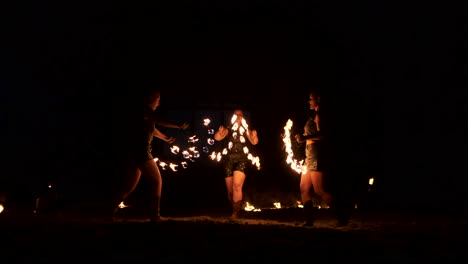 group of fire jugglers. people spit fire in a dark night outdoors performance.