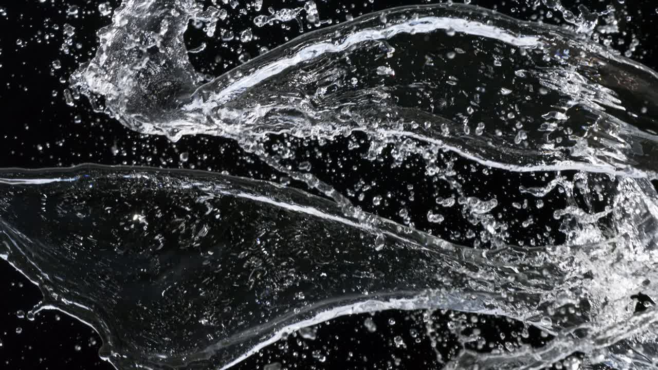 Collision of two water streams with splashes on black background