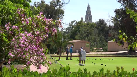 seniors engage in lawn bowling in san diego with old spanish colonial buildings background