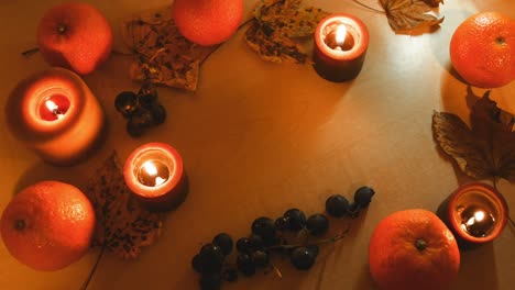 Detener-El-Movimiento-De-Un-Fondo-Otoñal-Con-Hojas,-Mandarina,-Castañas,-Velas-Y-Uvas