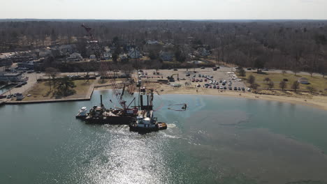 aerial pullback from boat launch where a tug boat and barge move in harbor