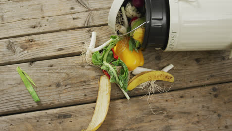 video of white compost bin with organic waste lying on grey wooden background