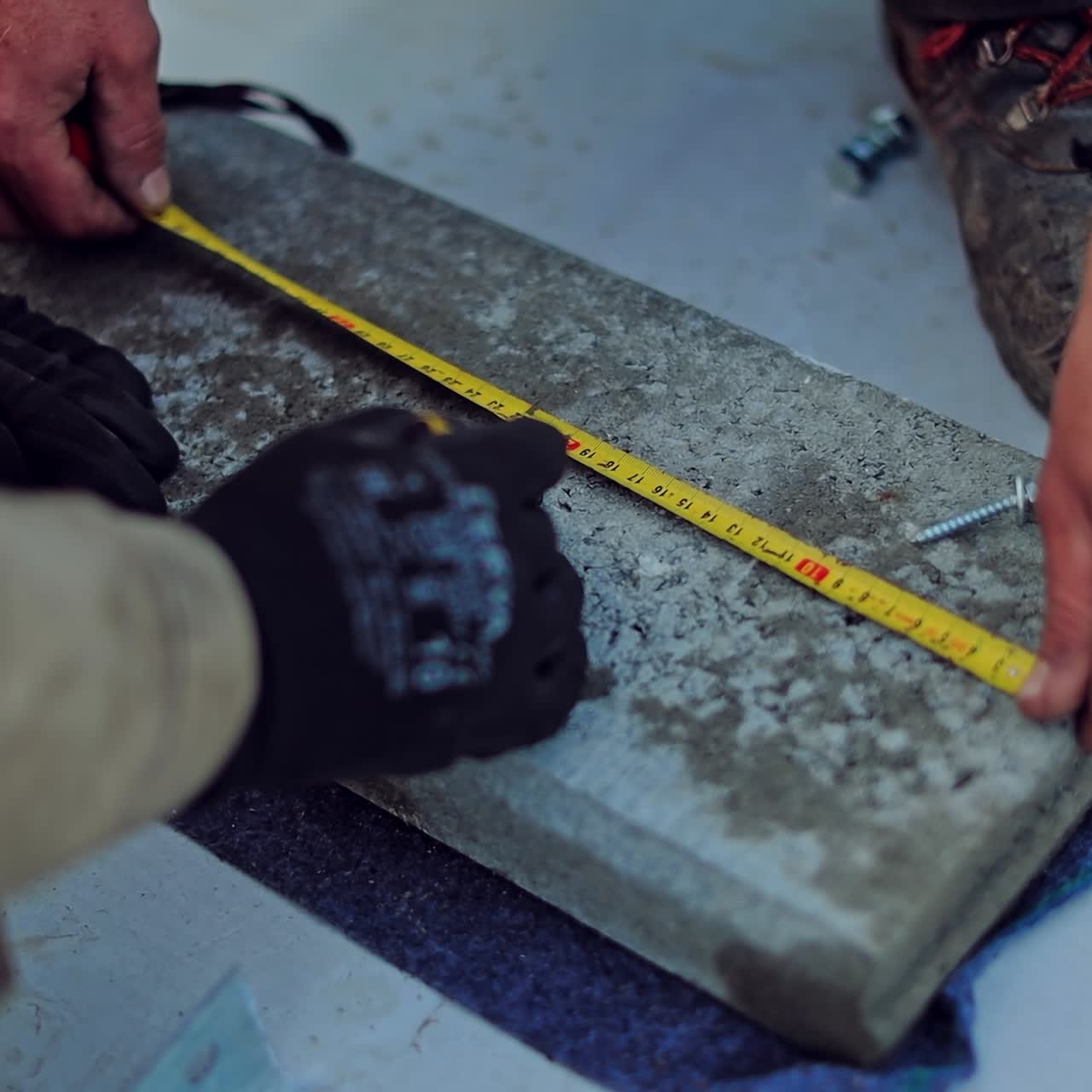 Engineering works. Technicians measuring concrete slab outdoors. Workers hands with meter during construction. Close-up.