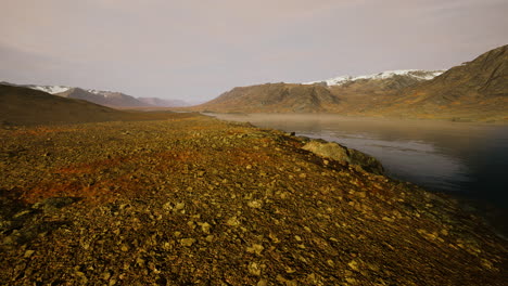 Clear-river-with-rocks-leads-towards-mountains-lit-by-sunset