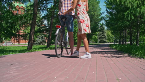 following a couple riding a bike through a park in summertime