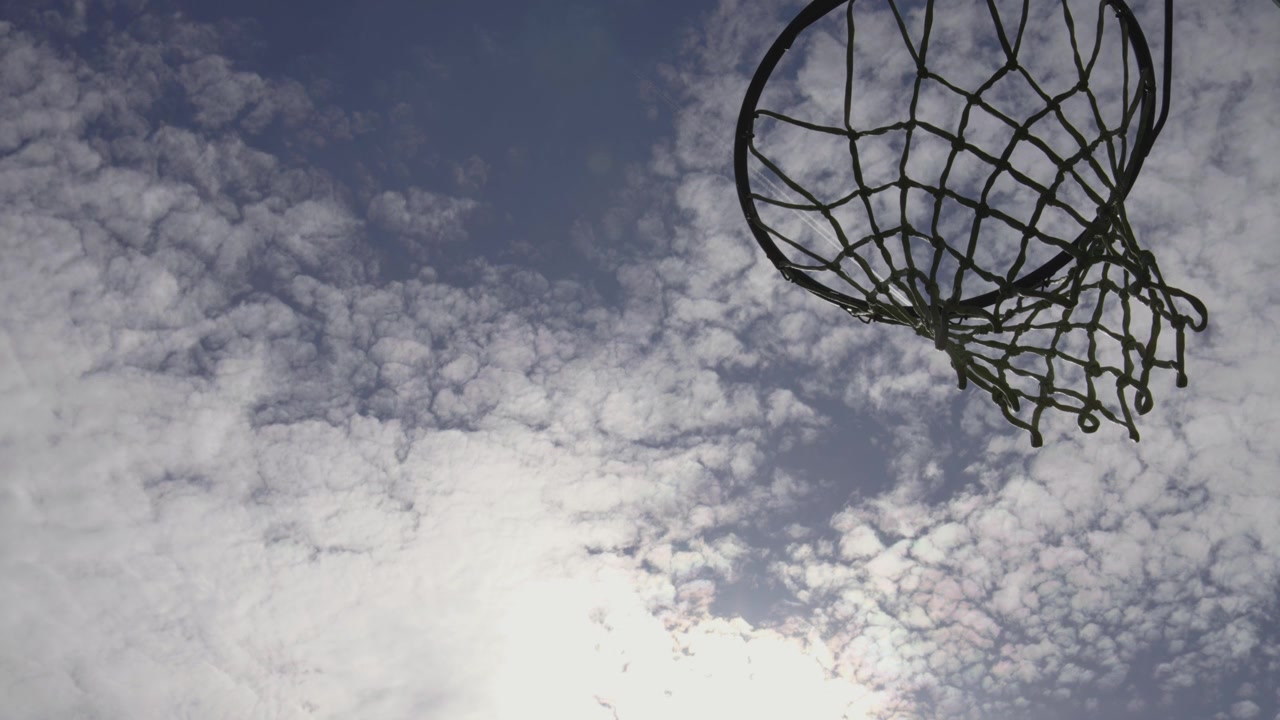 Silhouette di canestro da basket in un cielo blu nuvoloso con aerei che passano
