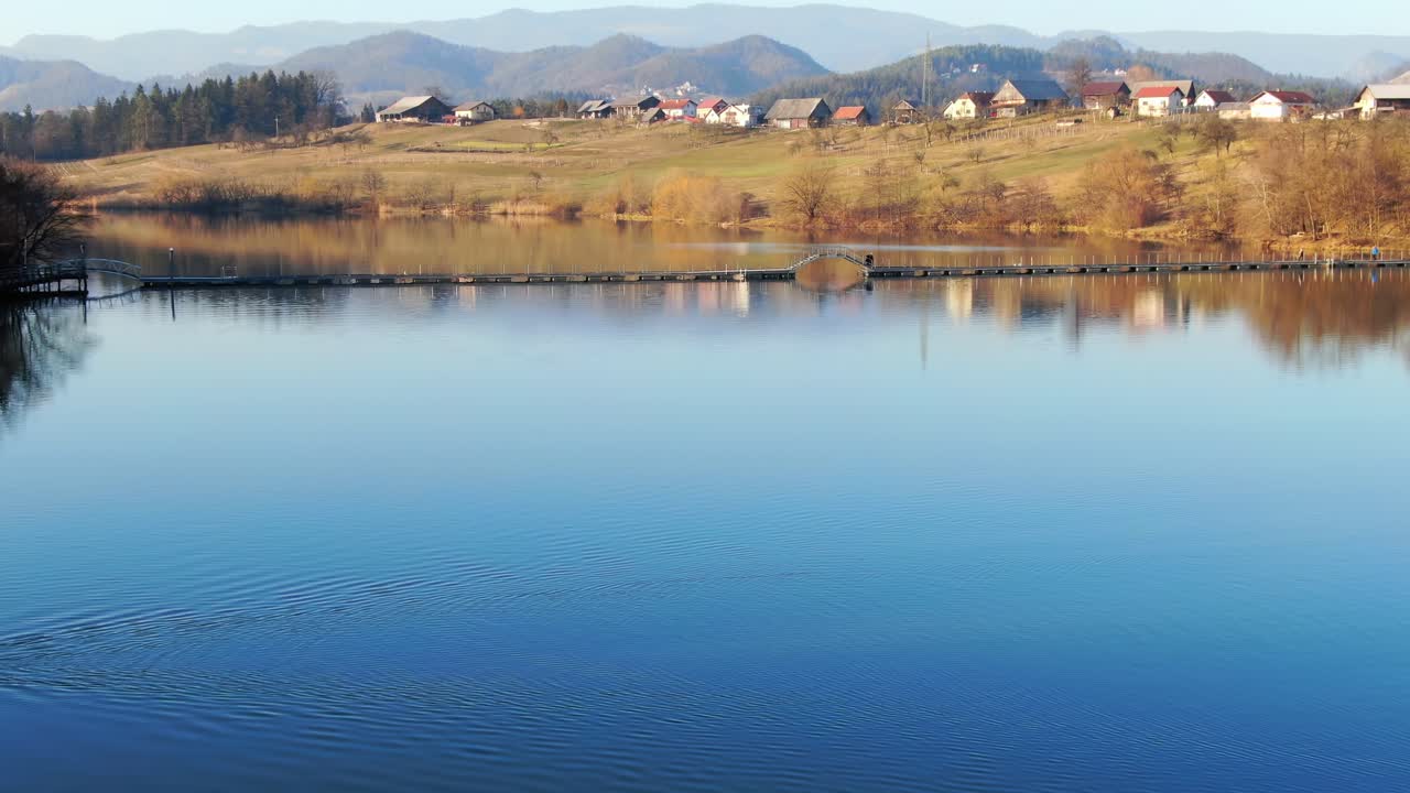Swans swim on calm waters of Smartinsko Lake in Slovenia. Aerial view