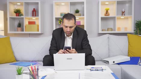 Home-office-worker-man-gets-frustrated-while-looking-at-phone.