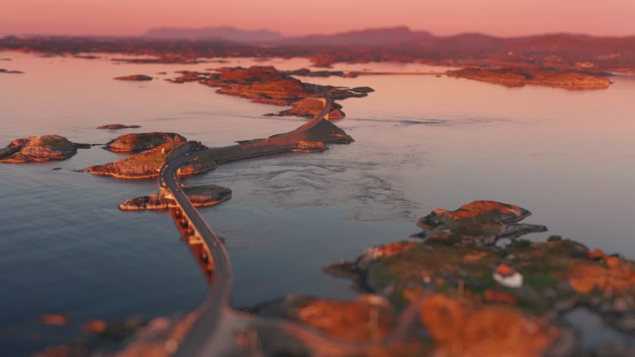 vista aérea de una serie de puentes de la famosa carretera atlántica que se extiende entre pequeñas islas rocosas, bañadas en los cálidos tonos de un sol poniente