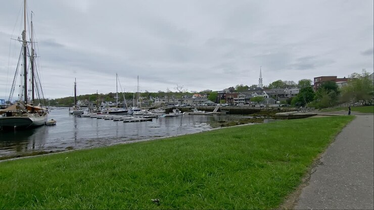 Inquadratura ampia del lungomare di Camden, Maine, con un sentiero e erba in primo piano.