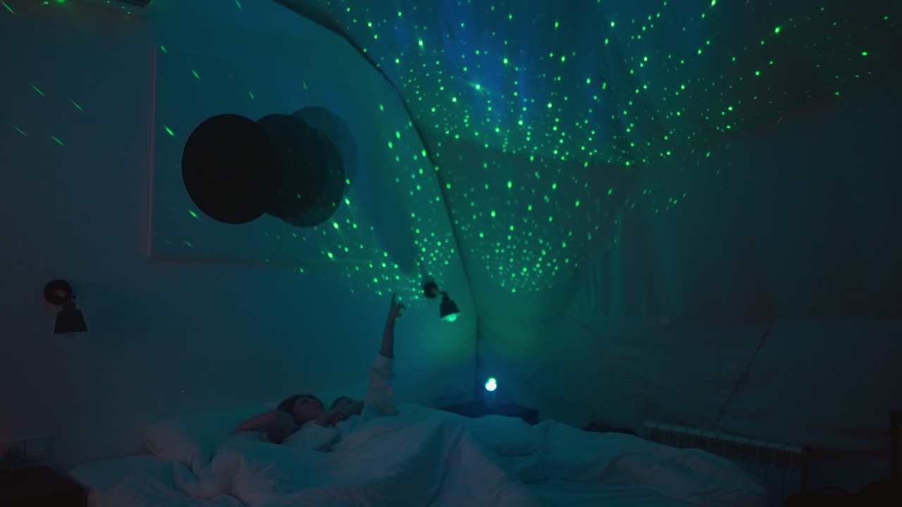 엄마는 천장에 손가락을 가리키며 눈 색 담요로 침대에 누워있는 아이에게 별을 보여줍니다. 편안한 분위기에서 잠자리에 들기 전에 엔터테인먼트와 휴식을 취합니다.