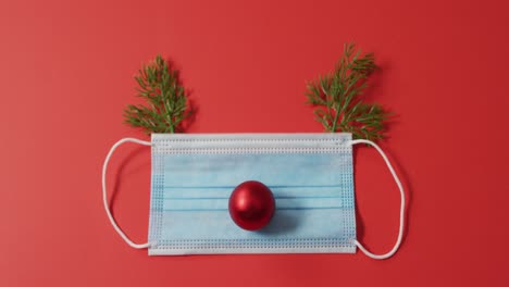 video of christmas decorations with face mask on red background