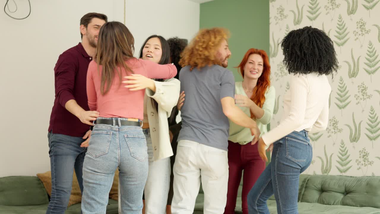 Multiethnic group of friends embracing happily and celebrating in apartment