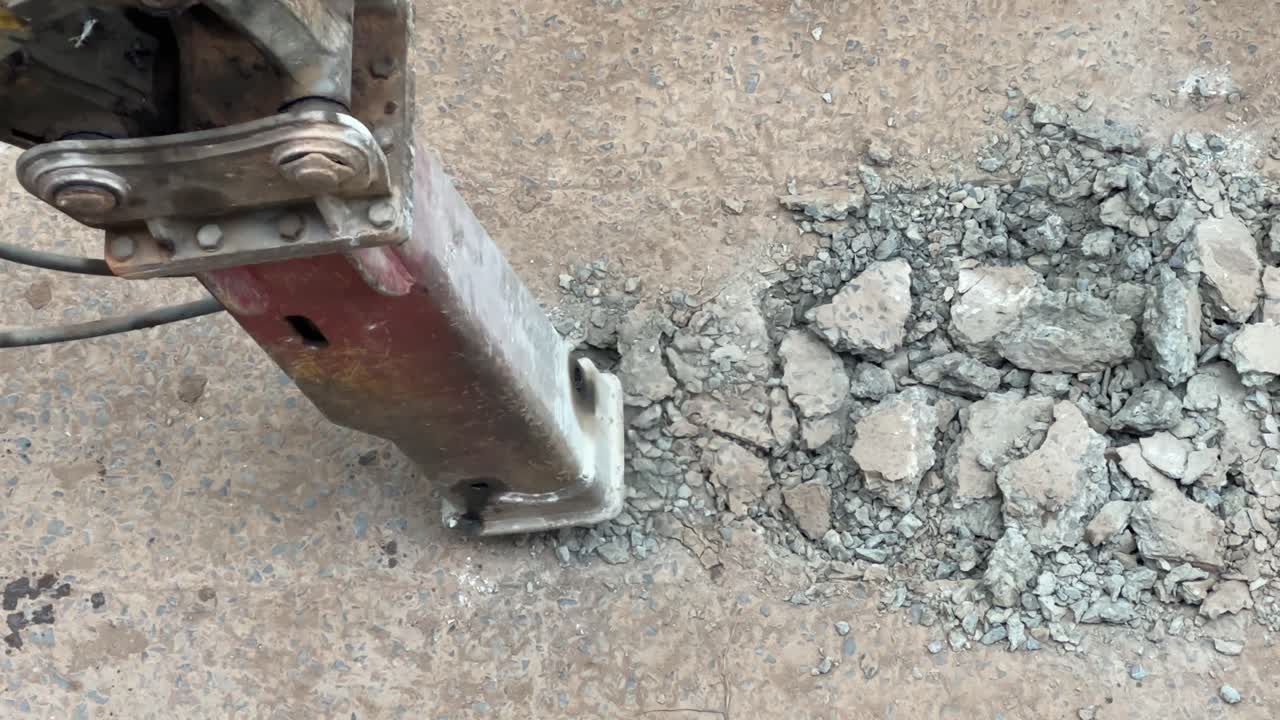 하수 노선 또는 도로 수리를 위해 콘크리트 도로를 깨뜨리고 굴착하는 발굴기의 근접 촬영