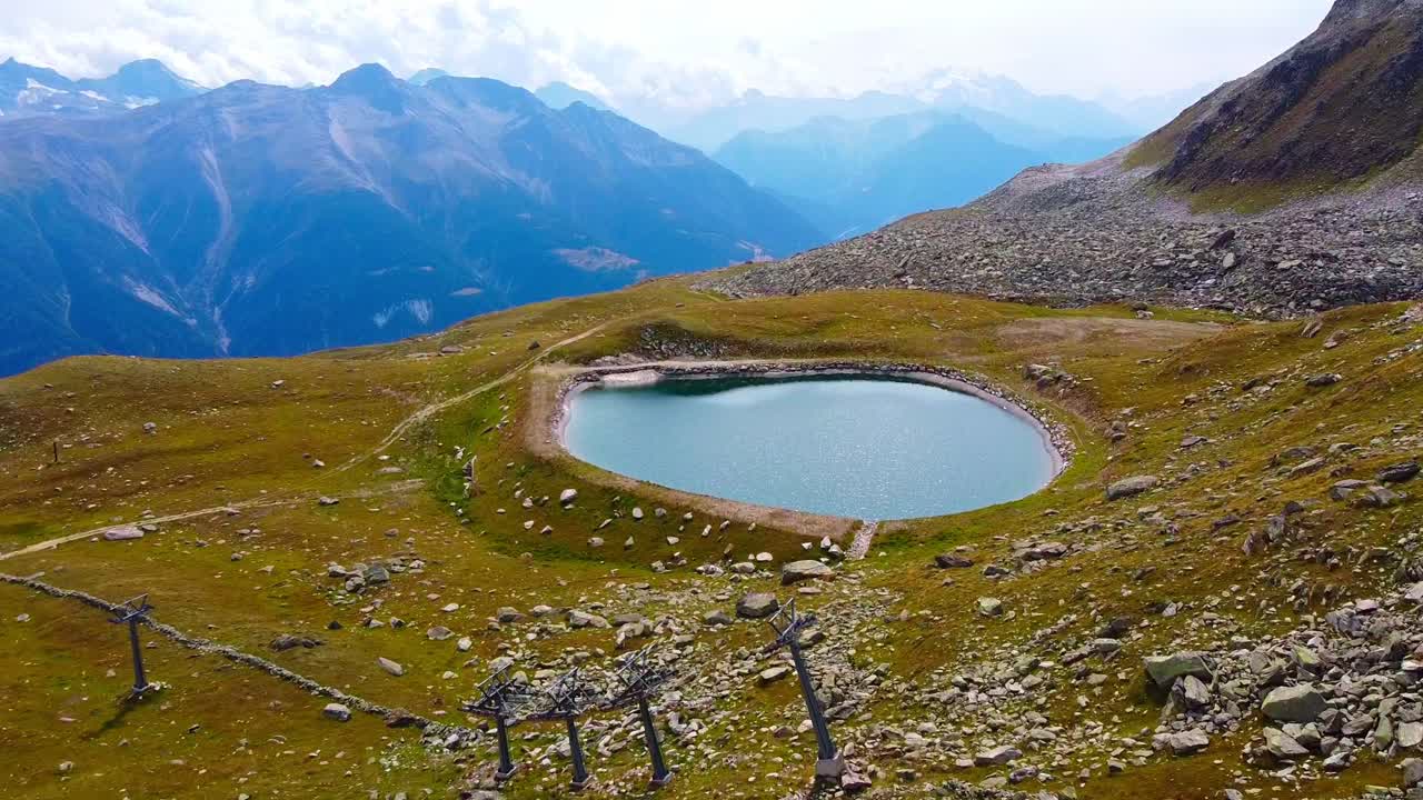 Aerial above scenic mountain lake, drink place for animals in the swiss alps near a hiking trail