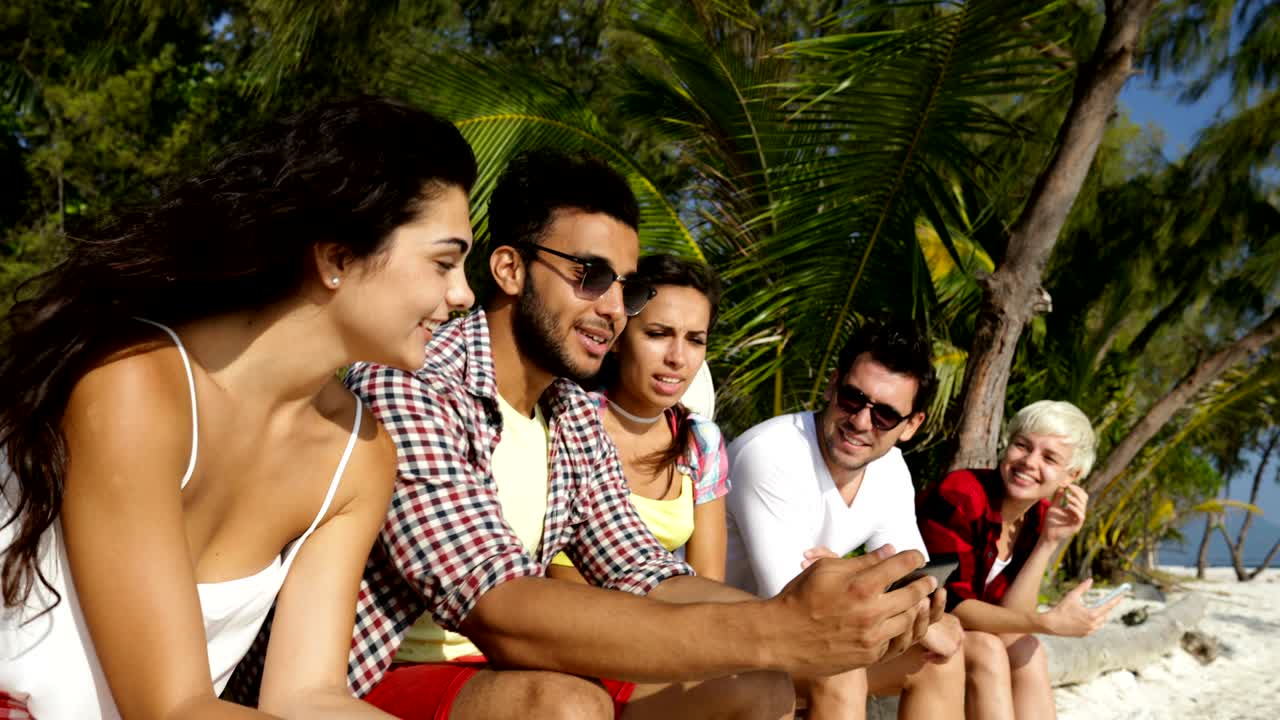 personas en grupo toman fotos de selfie en teléfonos inteligentes al aire libre bajo palmeras en la playa