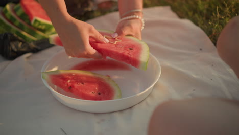 close-up of hand pressing star-shaped cutter into fresh watermelon slice on white plate, highlighting vibrant red flesh and green rind for a creative touch, watermelon