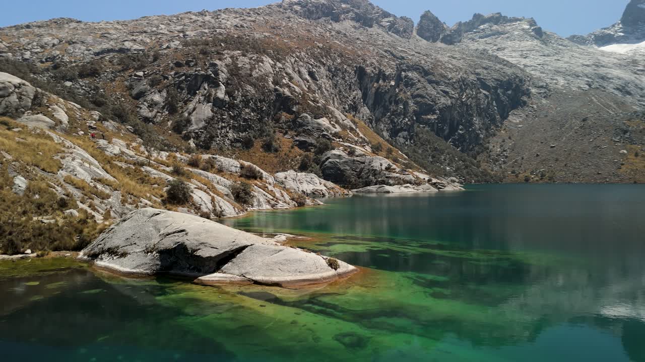 Stunning aerial panoramic view over Laguna Churup, showcasing its vivid turquoise waters surrounded by dramatic rocky slopes and high Andean peaks in Huascarán National Park