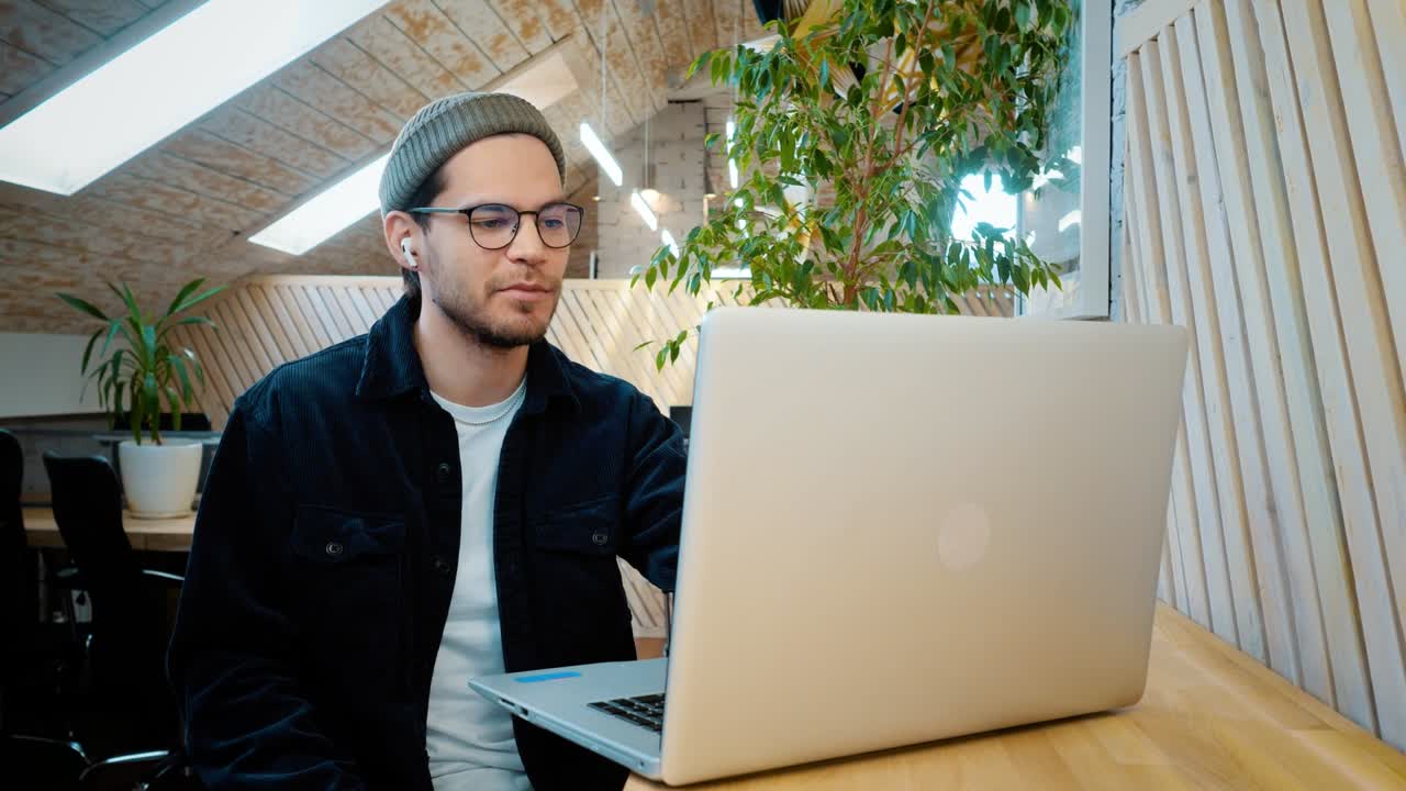 un joven se comunica a través de un enlace de video a través de una computadora portátil. riendo, bromeando. escucha al interlocutor