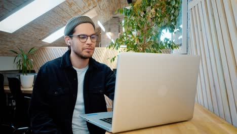 un joven se comunica a través de un enlace de video a través de una computadora portátil. riendo, bromeando. escucha al interlocutor