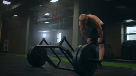 a tired man rests after lifting weights vilnay exercise deadlifts. preparing and adjusting concentration before training. mood and heavy breathing of an athlete with vapor in the gym