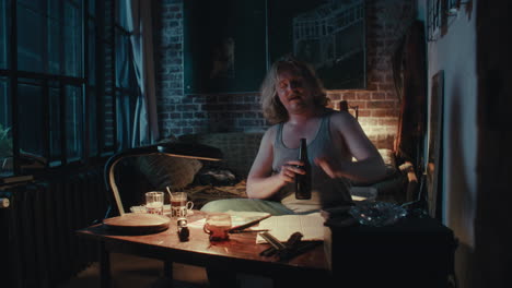 man drinking alone in his apartment at night