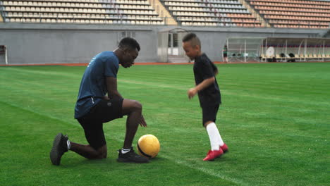 soccer coach training a young boy on a stadium field