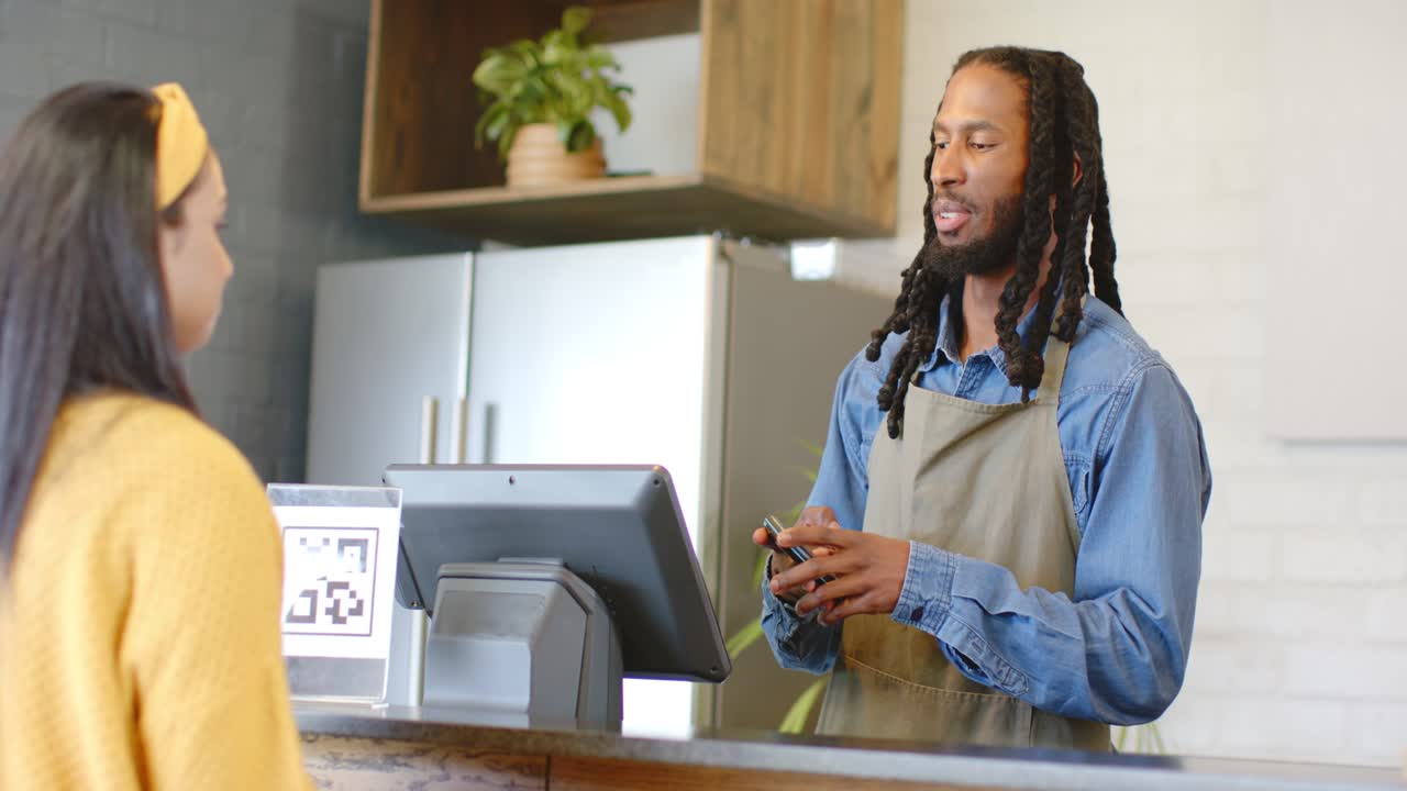 Cumprimento de barista afro-americano escaneando o código QR do pagamento pelo celular no balcão do café, espaço para texto