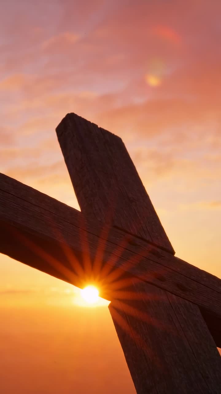 Cruz de madeira desgastada em silhueta contra o horizonte do pôr do sol com explosão solar e reflexo de lente.