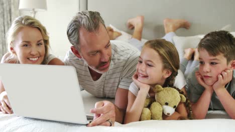 Family-using-laptop-while-lying-together-in-bedroom-at-home-4k