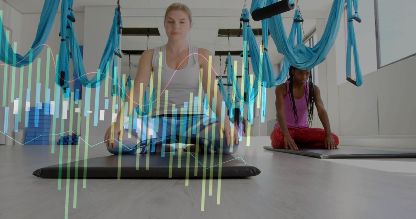 Instructor cueing student rising from kneeling mats to seated pose beneath hammocks for meditation