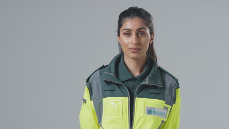 Studio-Portrait-Of-Serious-Young-Female-Paramedic-Against-Plain-Background