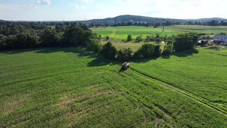 Una-Vista-Aérea-De-Un-Rociador-De-Cultivos-Agrícolas-Que-Conduce-Por-Un-Carril-De-Campo-En-Las-Tierras-De-Cultivo-Del-Condado-De-Lancaster,-Pennsylvania