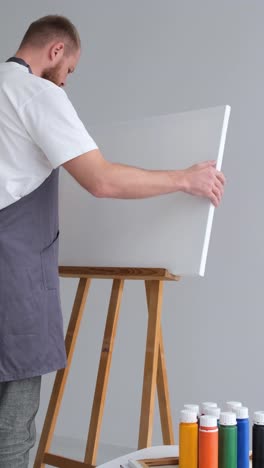 an artist preparing a blank canvas on an easel in a studio