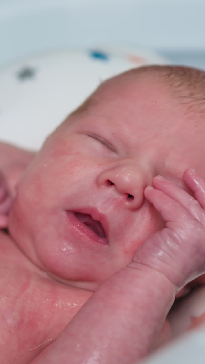 Un padre lava con delicadeza a su bebé recién nacido con agua tibia durante su rutina de baño