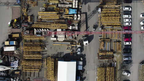 spinning tower crane with equipment and mast parts stored outside, aerial top down