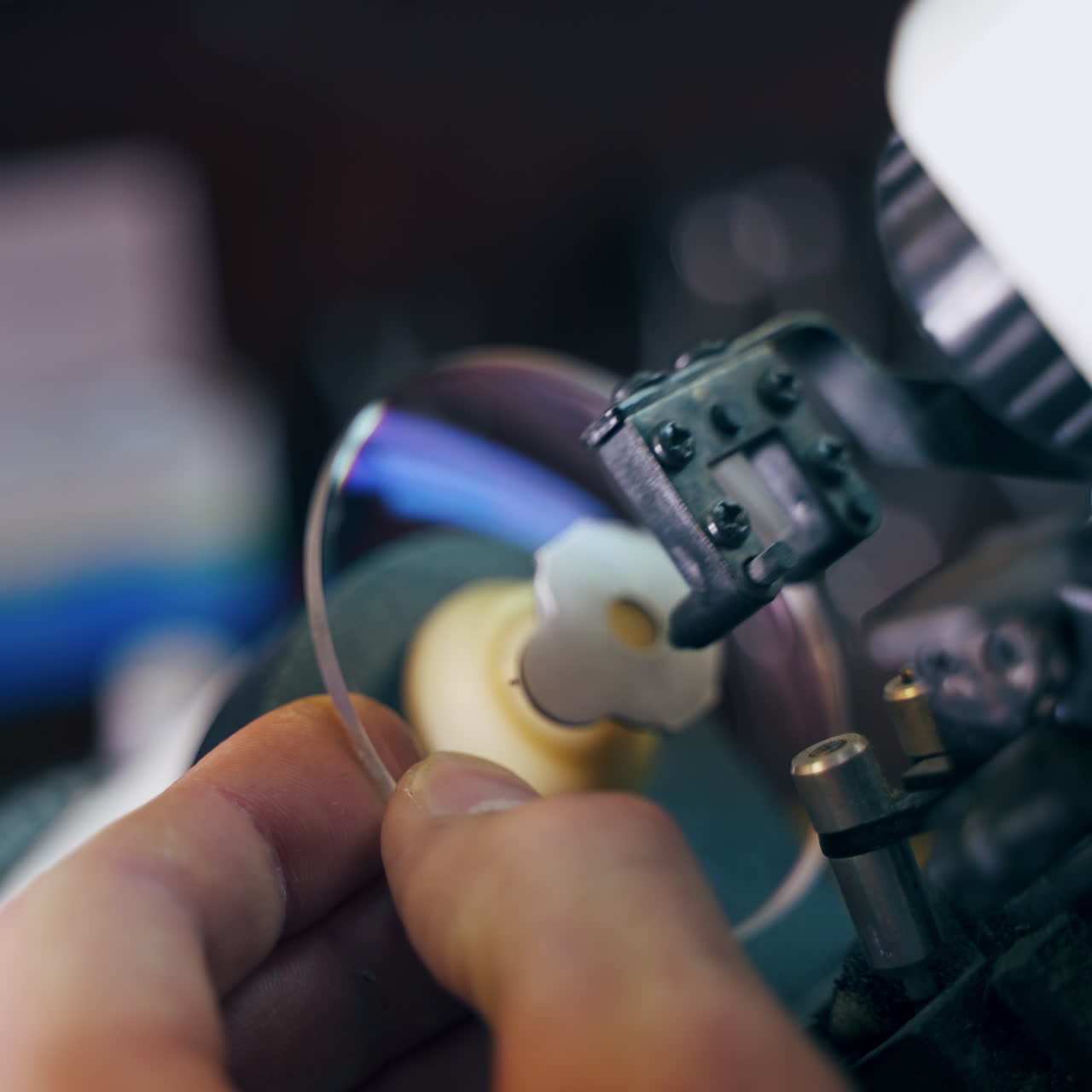 Manufacture of lenses for glasses. Close-up hands of optician making lense for eyeglasses on a modern equipment. Close-up.