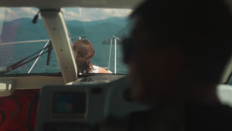 woman takes sunbathe on deck while skipper drives yacht in calm sea. lady enjoys motorboat trip with skilled captain on tropical vacation. boat cruise