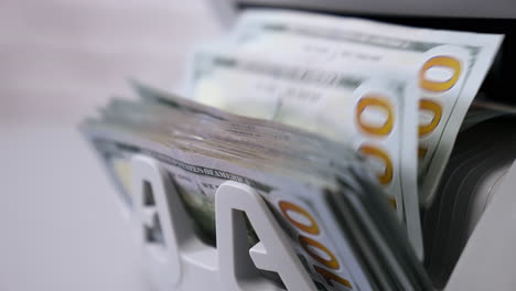 automatic calculation of paper money. detailed view of us dollar banknotes on currency counter machine. business economy of usa. macro shot.