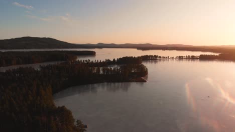 drone moving forward over the ice covered lake busjon outside applebo in vansbro kommun late in the day as the sun sets