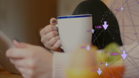 man holding mug and tapping device at wooden table, showing digital analytics graphics overlay