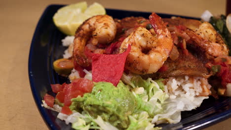 Mexican-shrimp-and-fish-over-rice-on-blue-triangle-plate,-slider-close-up-HD