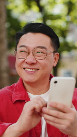 Asian-middle-aged-man-using-smartphone-typing-text-messages-in-social-media-application-online