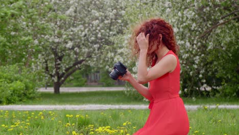 woman photographer in a red dress taking pictures in a spring park