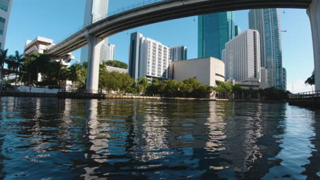 view-from-a-small-boat-as-it-passes-beneath-a-bridge-toward-tall-buildings-on-the-waterways-of-Miami-Florida-on-a-sunny-day