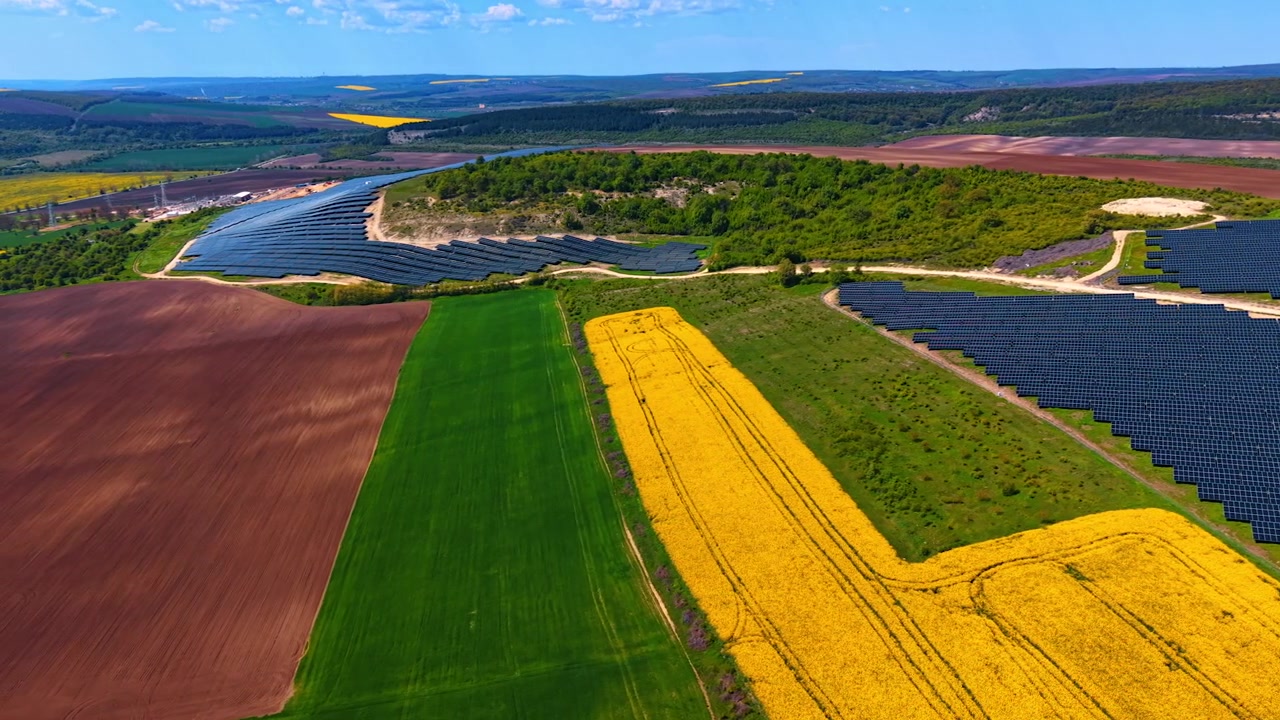 Panneaux solaires à côté de champs de colza et de terres agricoles vus d'en haut. Composition aérienne de rangées photovoltaïques à côté de sol labouré, de cultures vertes et de bandes de colza jaune en fleurs.